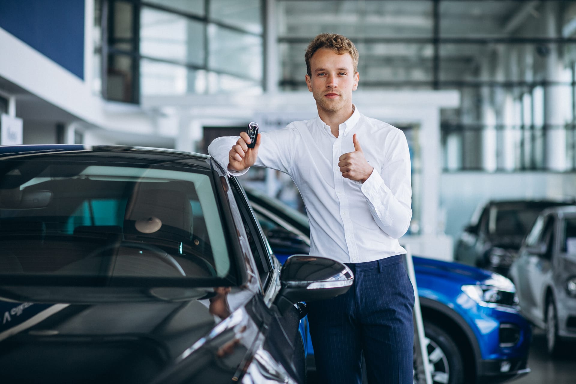 Young handsome man choosing a car in a car showroom