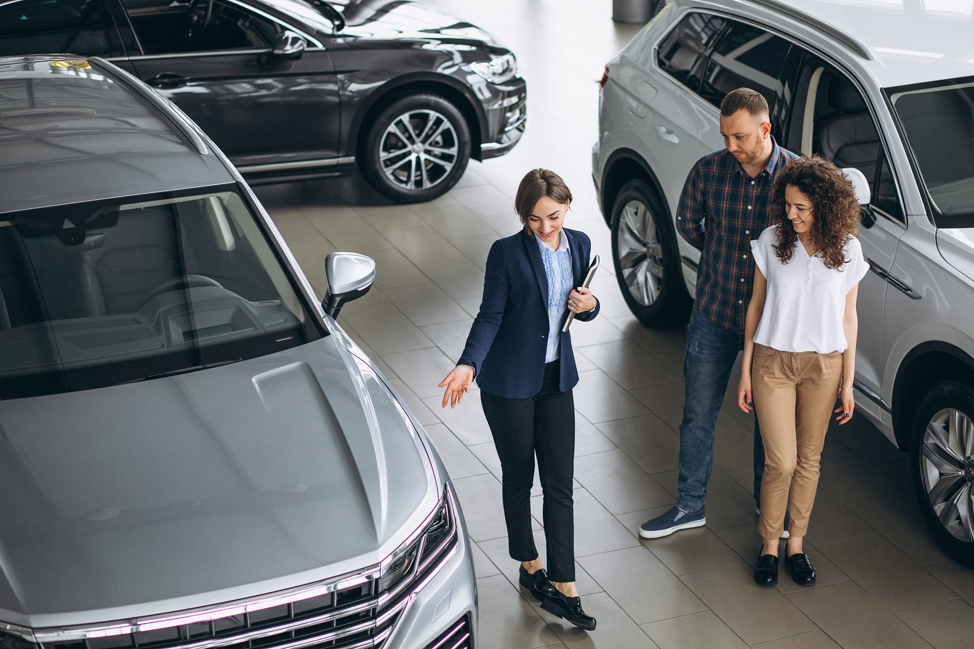 Young couple talking to a sales person in a car showroom