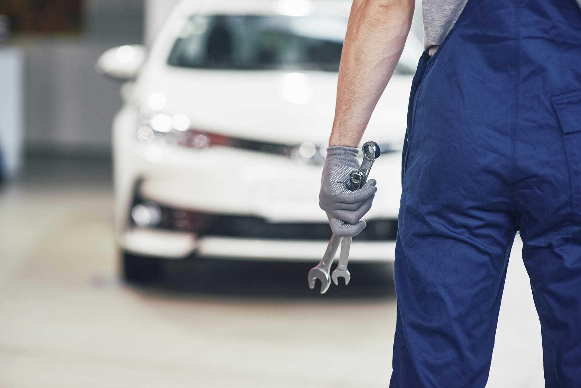 Hände eines Automechanikers mit Schraubenschlüssel in der Garage