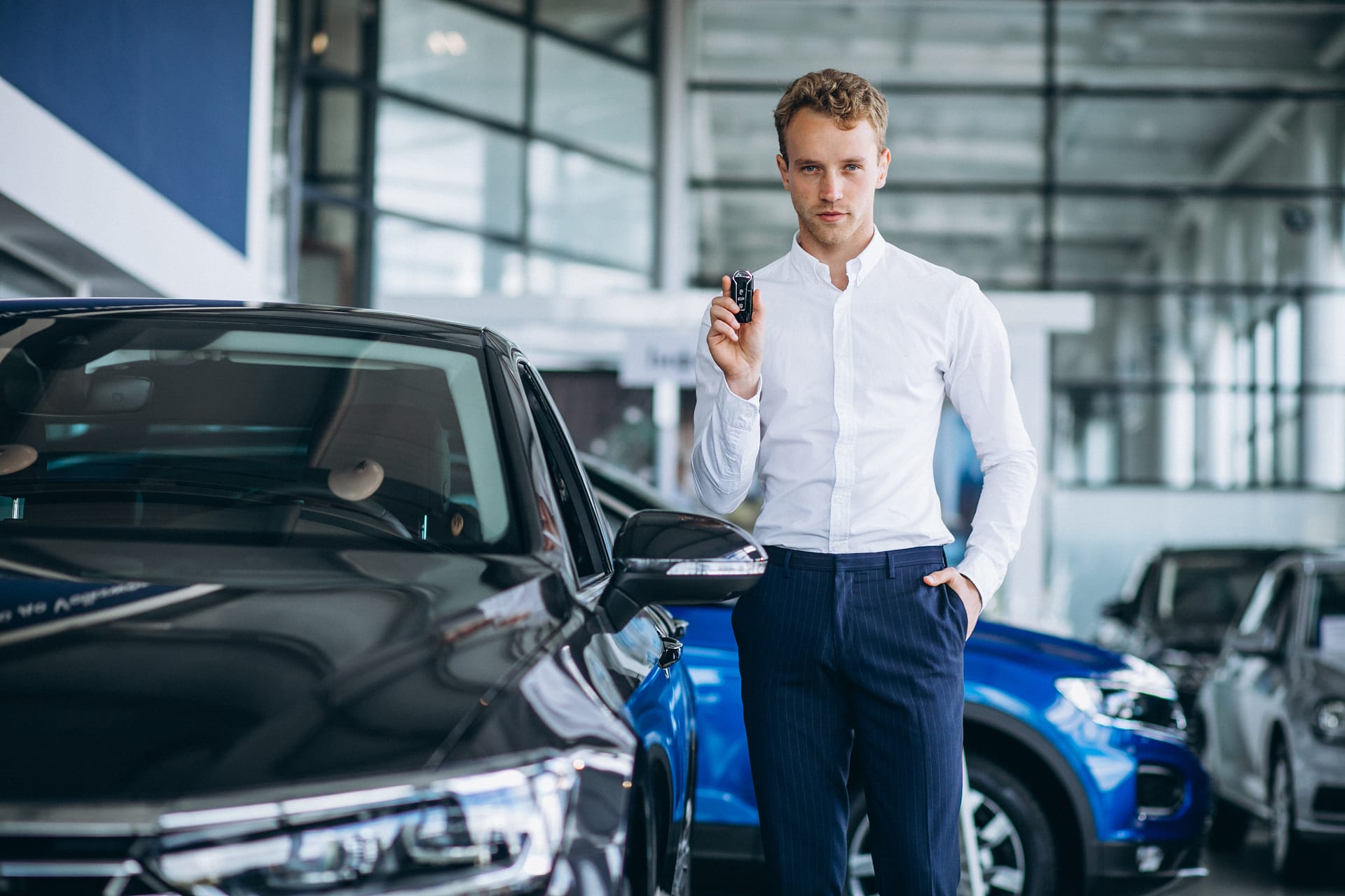 Young handsome man choosing a car in a car showroom