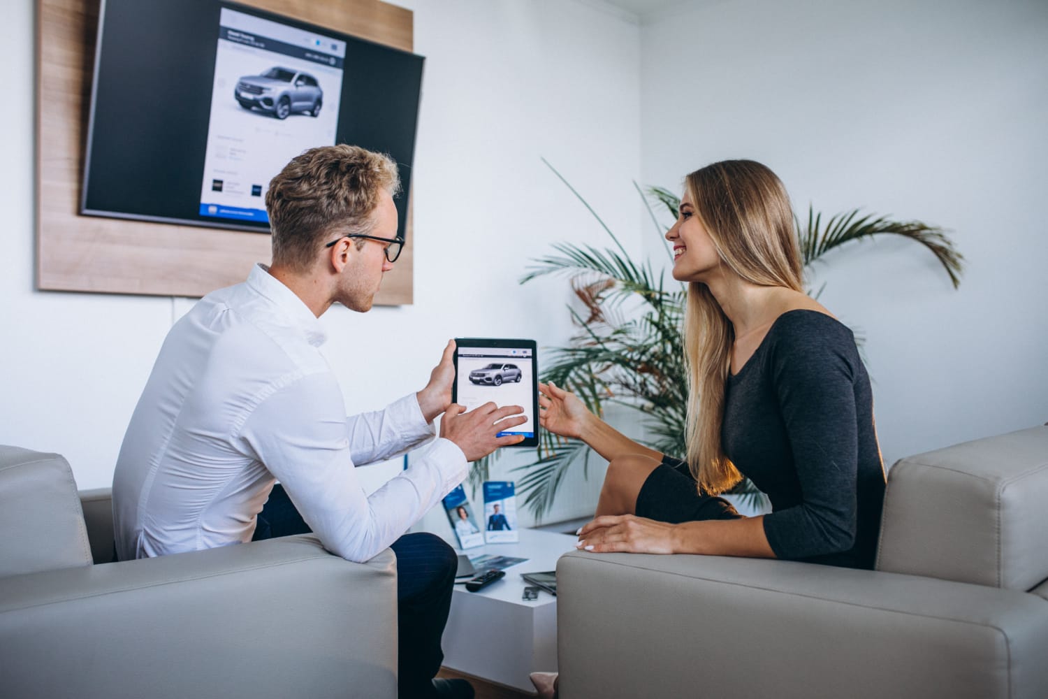 homme-et-femme-dans-un-showroom-de-voiture-utilisant-une-tablette